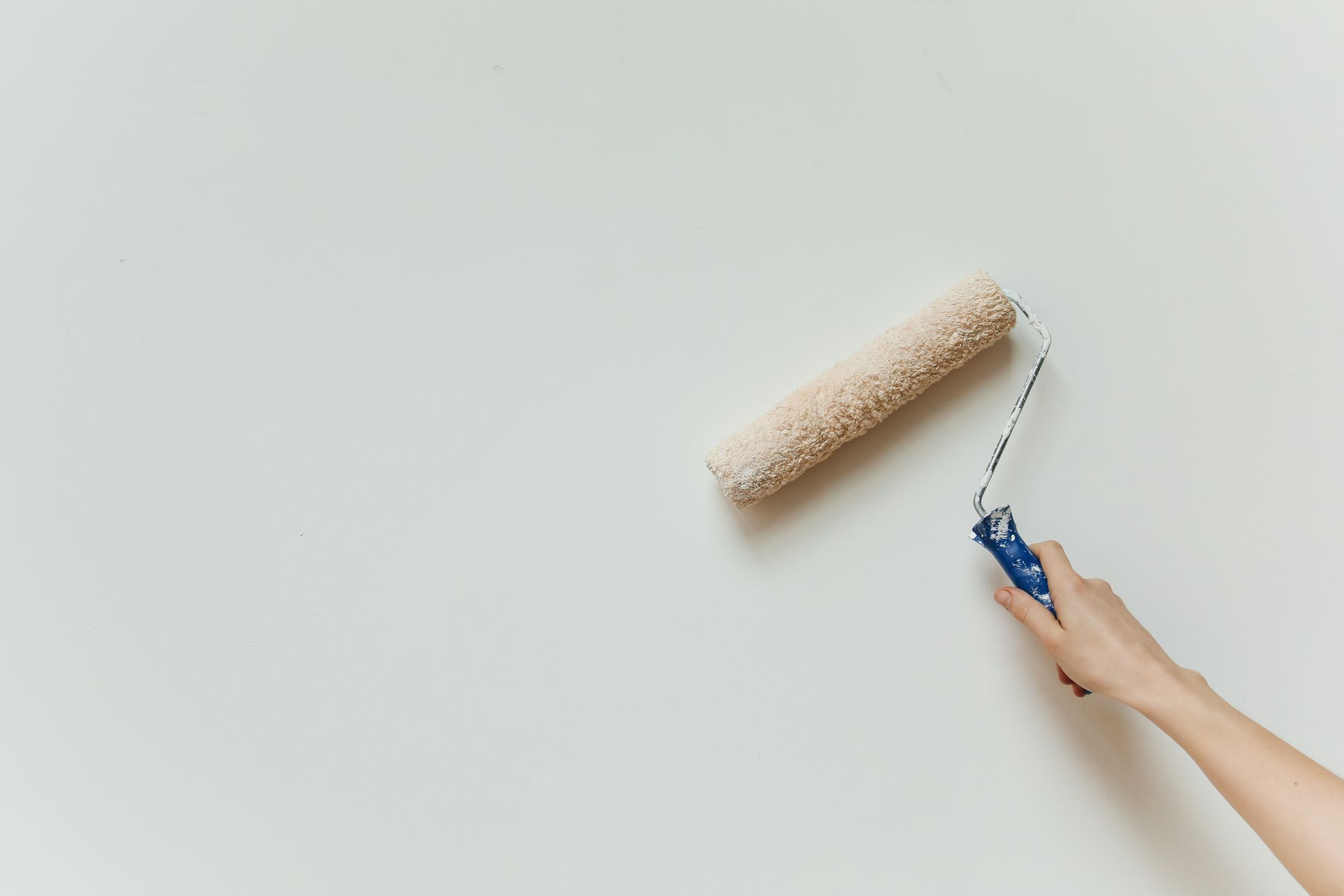 Rouleau de peinture appliqué sur un mur blanc